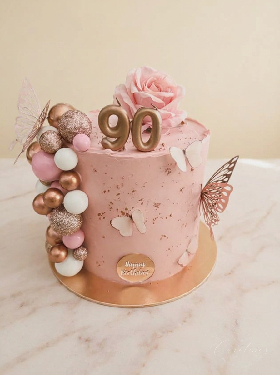 Blush pink 90th cake with rose-gold spheres, butterflies and a sugar rose