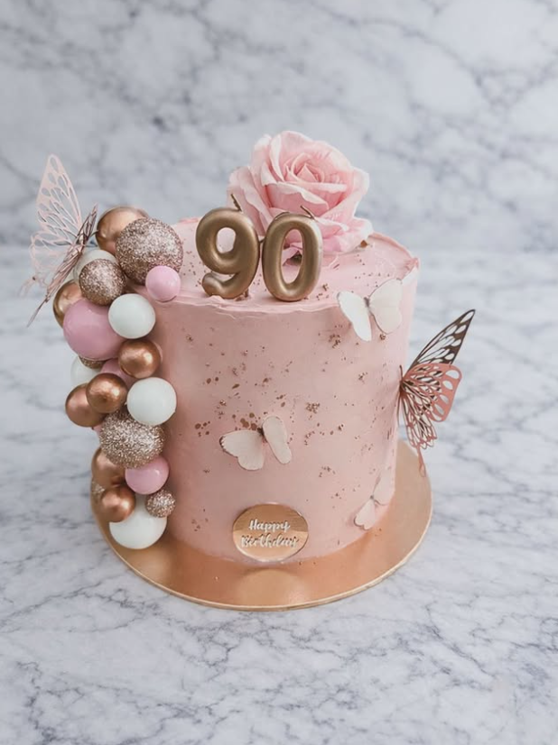 Blush pink 90th cake with rose-gold spheres, butterflies and a sugar rose