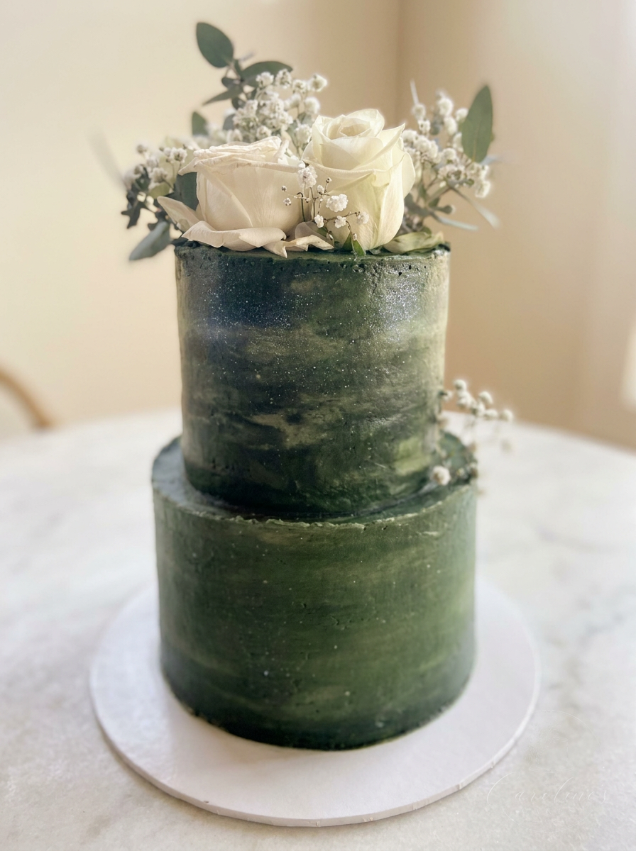 Two-tier deep green watercolour cake with white roses and baby's breath